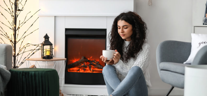 Woman,Drinking,Tea,Near,electric,Fireplace,At,Home