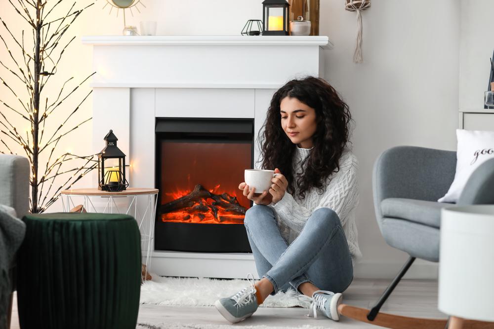 Woman,Drinking,Tea,Near,electric,Fireplace,At,Home